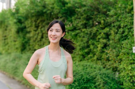 Photo for Fit young Asian woman jogging in park smiling happy running and enjoying a healthy outdoor lifestyle. Female jogger. Fitness runner girl in public park. healthy lifestyle and wellness being concept - Royalty Free Image
