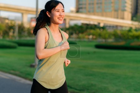 Foto de Ajuste joven mujer asiática corriendo en el parque sonriendo feliz corriendo y disfrutando de un estilo de vida saludable al aire libre. Una corredora. Chica corredor de fitness en el parque público. estilo de vida saludable y bienestar siendo concepto - Imagen libre de derechos