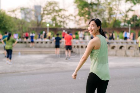 Foto de Una corredora. Ajuste Mujer joven asiática con ropa deportiva verde aeróbic ejercicio de baile en el parque y disfrutar de un sano al aire libre. Chica corredor de fitness en el parque público. Bienestar siendo concepto - Imagen libre de derechos