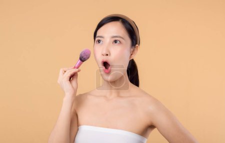Photo for Portrait young happy asian woman with natural make up face holding cosmetic skin powder blusher isolated on beige background. Female apply skincare brush treatment. beauty product cosmetology concept. - Royalty Free Image