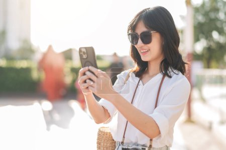 Photo for Portrait young beautiful asian woman using smartphone to video call with friend and explore street on summer vacation in Bangkok - Royalty Free Image