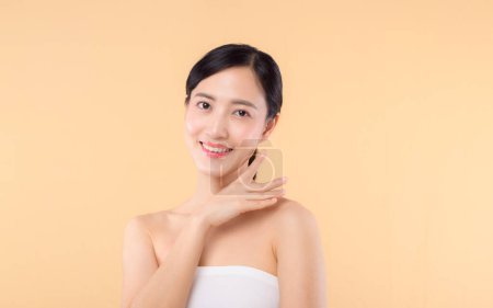 Photo for Beautiful asian girl model touching fresh glowing hydrated facial skin on beige background closeup. Beauty face young woman with natural makeup and healthy skin portrait. Skin care concept - Royalty Free Image