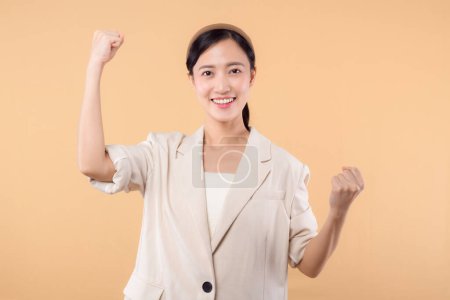 Téléchargez les photos : Studio portrait de heureux heureux heureux confiant jeune femme d'affaires asiatique. Belle jeune femme en veste blanche souriant à la caméra debout isolé sur fond de copyspace couleur beige uni - en image libre de droit