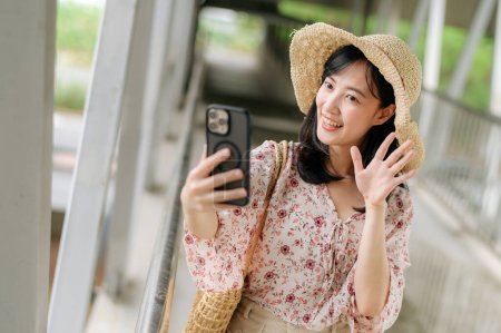 Foto de Asiático joven viajero con tejer cesta selfie con teléfono móvil y de pie en puente. Viaje viaje estilo de vida, viajero mundial o concepto de turismo de verano de Asia. - Imagen libre de derechos
