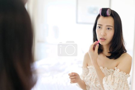 Foto de Hermosa mujer joven asiática que aplica maquillaje delante del espejo. Concepto de gente de estilo de vida. Anuncio de crema para la piel, crema anti-arrugas, cara de bebé - Imagen libre de derechos