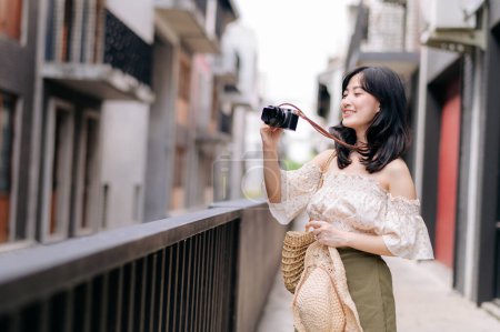 Téléchargez les photos : Heureuse jeune femme asiatique avec caméra voyage dans la rue voyage en week-end de loisirs. Jeune hipster femelle tourisme touristique été destination urbaine Bangkok. Asie concept de tourisme d'été. - en image libre de droit