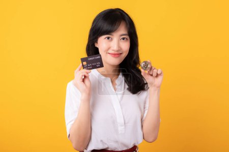 Photo for Portrait young beautiful asian woman enterpriser happy smile wearing white shirt and red plants holding credit card and crypto digital currency isolation on yellow background. Wealth concept. - Royalty Free Image