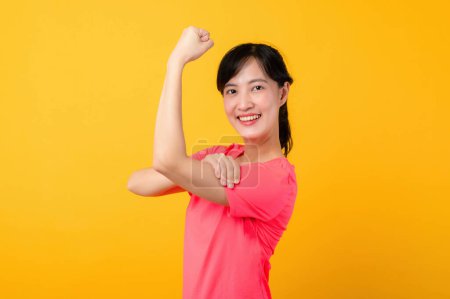 Foto de Retrato joven hermosa asiática deportes fitness mujer feliz sonrisa usando ropa deportiva rosa posando ejercicio entrenamiento de entrenamiento aislado sobre fondo de estudio amarillo. bienestar y concepto de estilo de vida saludable. - Imagen libre de derechos