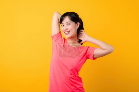 Téléchargez les photos : Portrait jeune belle asiatique sport fitness femme heureux sourire portant des vêtements de sport rose posant entraînement exercice séance d'entraînement isolé sur fond jaune studio. bien-être et mode de vie sain concept. - en image libre de droit