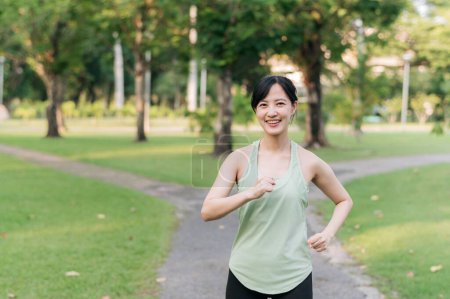 Photo for Fit Asian young woman jogging in park smiling happy running and enjoying a healthy outdoor lifestyle. Female jogger. Fitness runner girl in public park. healthy lifestyle and wellness being concept - Royalty Free Image
