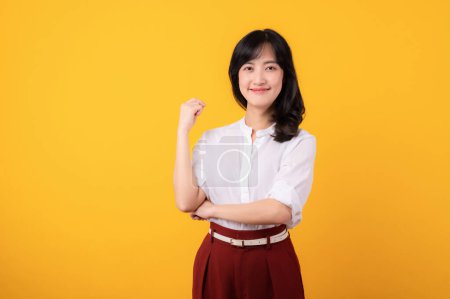 Téléchargez les photos : Portrait asiatique jeune femme entrepreneuse heureux sourire vêtu de chemise blanche et de plantes rouges montrant un geste confiant langage du corps isolé sur fond jaune. - en image libre de droit