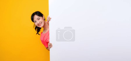 Photo for Asian young sports fitness woman happy smile wearing pink sportswear standing behind the white blank banner or empty space advertisement board against yellow background. wellbeing lifestyle concept. - Royalty Free Image