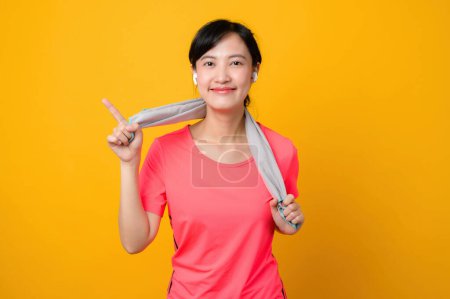Photo for Portrait asian young sports fitness woman happy smile wearing pink sportswear and face towel doing exercise training workout against yellow studio background. wellbeing and healthy lifestyle concept. - Royalty Free Image