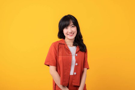 Photo for Portrait young beautiful asian woman cute and shy dressed in orange clothes isolated on yellow studio background. - Royalty Free Image