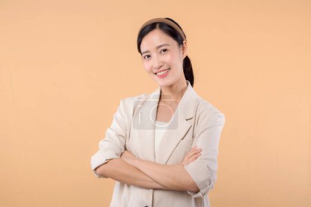 Foto de Estudio retrato de éxito feliz confiado joven asiático mujer de negocios. Hermosa joven en chaqueta blanca sonriendo a la cámara de pie aislado sobre fondo de copyspace de color beige sólido - Imagen libre de derechos