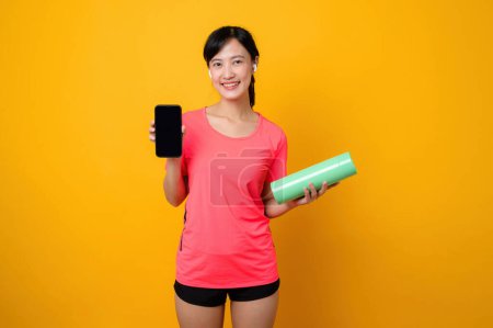 Photo for Portrait asian young sports fitness woman happy smile wearing pink sportswear and smartphone doing exercise training workout against yellow studio background. technology wellness lifestyle concept. - Royalty Free Image