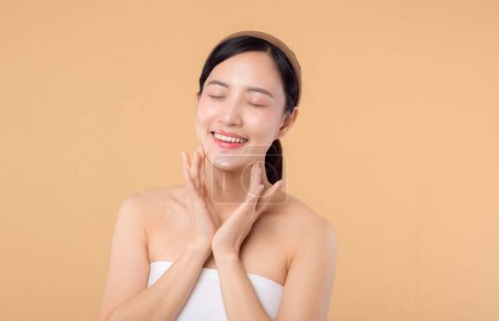 Photo for Beautiful asian girl model touching fresh glowing hydrated facial skin on beige background closeup. Beauty face young woman with natural makeup and healthy skin portrait. Skin care concept - Royalty Free Image