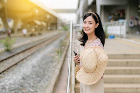 Photo for Asian young woman traveler with weaving basket waiting for train in train station. Journey trip lifestyle, world travel explorer or Asia summer tourism concept. - Royalty Free Image