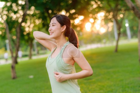 Photo for Female jogger. Fit Asian young woman with green sportswear stretching muscle in park before running and enjoying a healthy outdoor. Fitness runner girl in public park. Wellness being concept - Royalty Free Image