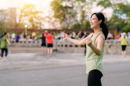Téléchargez les photos : Joggeuse. Adaptez-vous à une jeune femme asiatique avec des vêtements de sport verts exercice de danse aérobie dans le parc et profiter d'un plein air sain. Fitness fille coureuse dans le parc public. Concept de bien-être - en image libre de droit