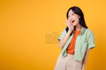Foto de Empresaria asiática de unos 30 años hablando en un estudio. Grita, sonríe y gesticula con la mano aislada sobre fondo amarillo. las empresas, la comunicación y las mujeres en el concepto de fuerza laboral. - Imagen libre de derechos
