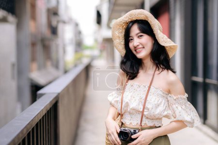 Téléchargez les photos : Heureuse jeune femme asiatique avec caméra voyage dans la rue voyage en week-end de loisirs. Jeune hipster femelle tourisme touristique été destination urbaine Bangkok. Asie concept de tourisme d'été. - en image libre de droit