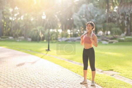 Foto de Una corredora. Activa joven mujer asiática de 30 años en ropa deportiva rosa disfruta de un entrenamiento matutino en la naturaleza. activa y vivir un concepto de estilo de vida saludable. - Imagen libre de derechos