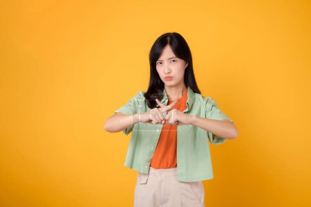 Photo for Portrait asian young 30s woman expression serious negative face and showing cross finger deny hand gesture isolated on yellow background. wrong, no, stop and rejection body sign symbol concept - Royalty Free Image