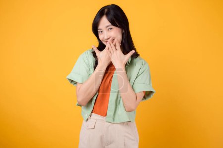 Photo for Shy asian young woman 30s covering her mouth with hands isolated on yellow background. expression of embarrassment or uncertainty. shyness, embarrassment, and body language concept. - Royalty Free Image