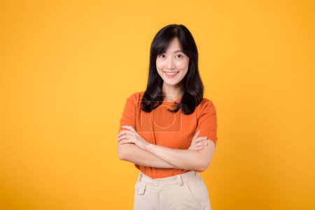 Photo for Confident young Asian woman 30s, wearing an orange shirt, showcases crossed arm sign gesture on yellow background. Hands gesture concept. - Royalty Free Image