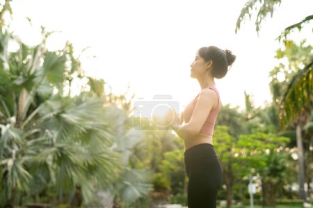 Foto de Bienestar y bienestar en forma joven mujer asiática de 30 años en ropa deportiva rosa se dedica al yoga y estira sus músculos en un parque. Abrace un estilo de vida saludable al aire libre con chica de yoga fitness en el parque público. - Imagen libre de derechos