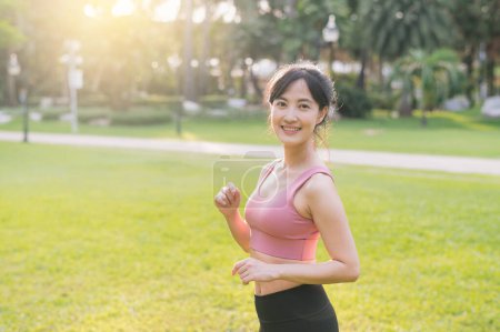 Foto de Captura la felicidad de una joven y hermosa mujer asiática de 30 años mientras sonríe y mira a la cámara en un parque al atardecer. Experimente el concepto de vida de bienestar. - Imagen libre de derechos