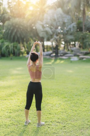 Photo for Female jogger. Back portrait of 30s asian woman wearing pink sportswear, breathing fresh air and preparing body before running in public park, sunset time. wellness healthy lifestyle, fitness concept. - Royalty Free Image