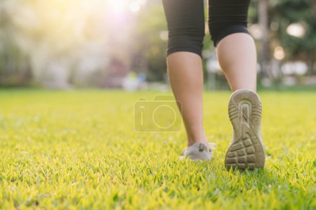 Téléchargez les photos : Joggeuse. close up personne entraînement sportif coureur jeune chaussure féminine sur les herbes dans le parc public. fitness pied et jambe athlète d'exercice. marathon dans la nature. mode de vie sain et actif concept d'entraînement. - en image libre de droit