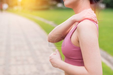 Téléchargez les photos : Joggeuse. 30s jeune asiatique femme portant rose vêtements de sport tenant son mal de dos après avoir couru exercice dans le parc public. Concept de douleur dans l'activité. - en image libre de droit