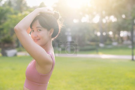 Photo for Capture the essence of wellness living with a happy, beautiful Asian woman 30s smiling at the camera in a park at sunset. Embrace the concept of wellness and joy. - Royalty Free Image