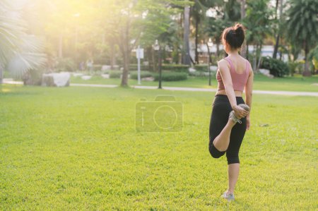 Photo for Female jogger, fit young Asian woman 30s wearing pink sportswear, warms up body in park before run. healthy outdoor lifestyle fitness runner girl, at sunset. wellness and well-being concept. - Royalty Free Image