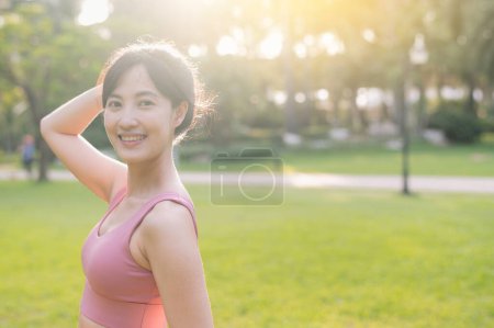 Téléchargez les photos : Vivez la joie de vivre bien-être comme une belle femme asiatique heureuse 30s sourit et regarde la caméra dans un parc au coucher du soleil. - en image libre de droit