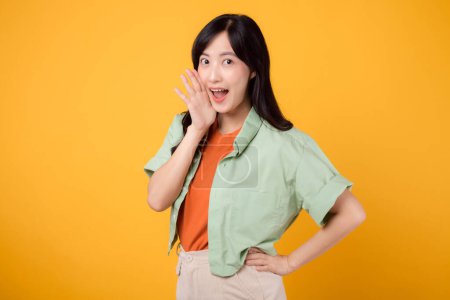 Lebendiges Bild junge asiatische Frau in den 30er Jahren in grünem Hemd auf orangefarbenem Hintergrund, energisch schreiend vor Aufregung. Entdecken Sie das Konzept der Discount-Shopping-Förderung mit diesem dynamischen Bild.