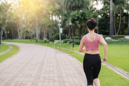 Foto de Una corredora. atrás perspectiva retrato de asiático joven mujer usando rosa sportswear correr en público parque. Concepto de salud y bienestar. - Imagen libre de derechos