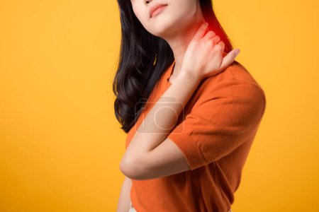 Foto de Mujer asiática empática de 30 años, vistiendo una camisa naranja, sostiene su dolor en el cuello sobre un fondo amarillo. síndrome de oficina concepto de atención médica. - Imagen libre de derechos