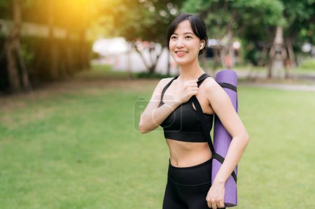 Photo for Portrait of young asian slim and healthy girl doing workout in park, standing with rubber mat for exercises on green park, healthcare and well-being and yoga concept. - Royalty Free Image