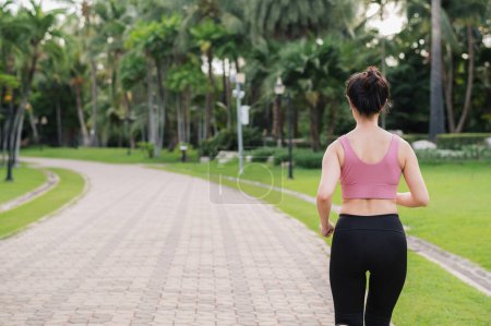 Téléchargez les photos : Joggeuse. retour perspective portrait de la jeune femme asiatique portant des vêtements de sport rose courir dans le parc public. Concept bien-être des soins de santé. - en image libre de droit