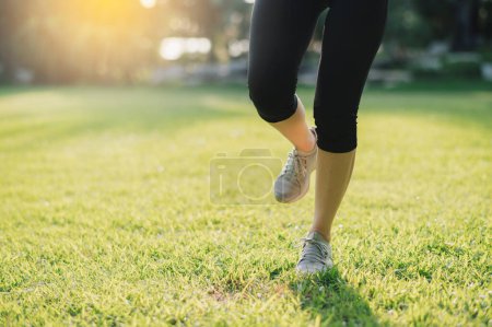 Découvrez la vue rapprochée des jambes et des chaussures de joggeuse lorsqu'elle court au coucher du soleil dans un parc public. Adoptez le concept de vie bien-être.