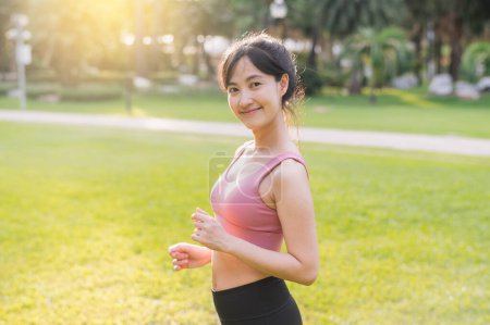 Photo for Experience the joy of wellness living as a happy, beautiful Asian woman 30s smiles and looks at the camera in a park at sunset. - Royalty Free Image
