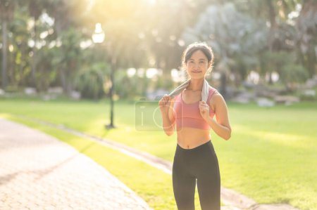 Téléchargez les photos : Fit femme joggeuse, heureuse femme asiatique trentaine en vêtements de sport, profiter d'un coucher de soleil rafraîchissant courir dans la nature. Adoptez les concepts de forme physique, de santé et de motivation avec cette silhouette captivante. - en image libre de droit