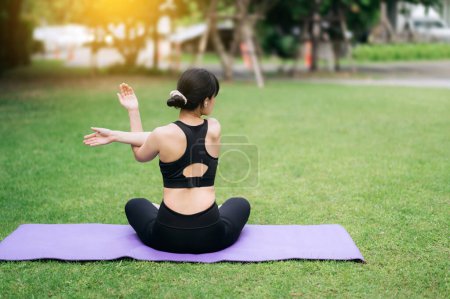 Téléchargez les photos : Portrait fit jeune femme asiatique en vêtements de sport rose avec tapis de yoga. étirement des muscles dans le parc. Connectez-vous à la sérénité de la nature grâce à la forme physique consciente. voyage de la femme vers le bien-être et la santé. - en image libre de droit
