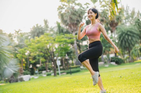 Téléchargez les photos : Fit femme asiatique dans la trentaine portant des exercices de vêtements de sport roses dans le parc public au coucher du soleil. Adoptez un mode de vie sain en plein air et découvrez l'essence du bien-être et du bien-être. - en image libre de droit
