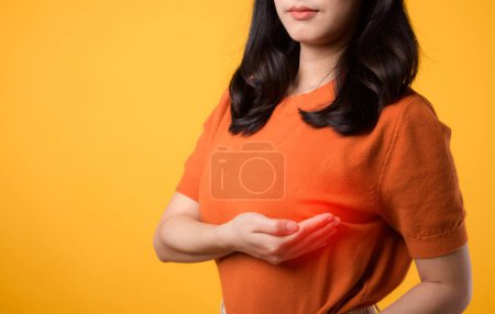 Photo for Take charge of breast health on World Health Day, woman checking for breast cancer signs on yellow studio background. - Royalty Free Image
