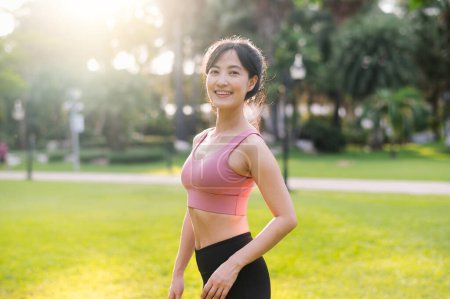 Téléchargez les photos : Découvrez la joie de vivre bien-être comme une femme asiatique heureuse 30s regarde la caméra avec un sourire dans un parc au coucher du soleil. Adopter le concept de bien-être. - en image libre de droit